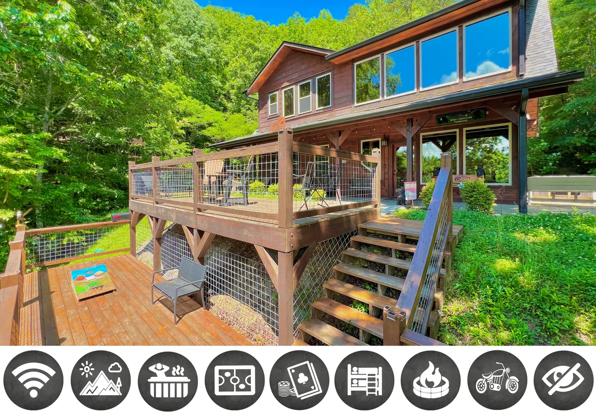 The hero image showcases the cabin's inviting exterior, centered on a spacious wooden deck with ample seating for outdoor dining and relaxing. Large windows reflect the surrounding greenery, while sturdy wooden stairs lead up to the entry. The scene is bathed in warm sunset light, highlighting the peaceful, secluded mountain setting.
