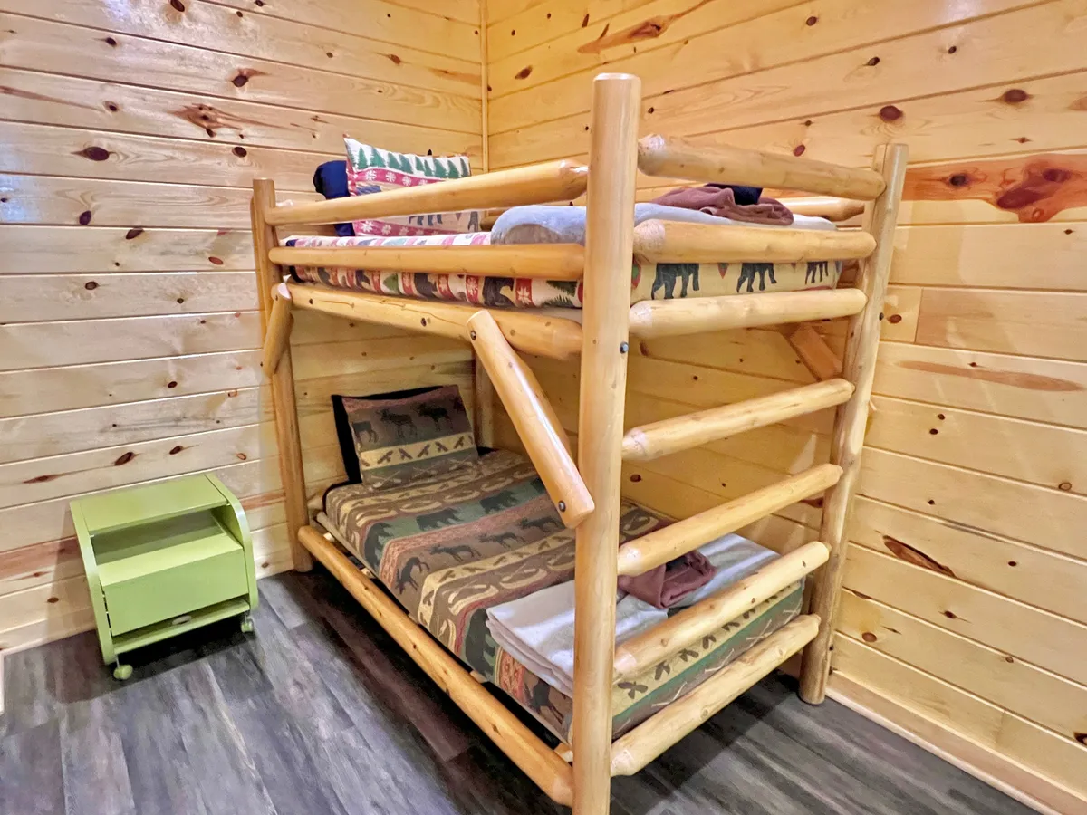 Here, the image spotlights a twin bunk bed in a cozy nook of the loft, complete with a green nightstand and decorative pillows. The inviting arrangement is perfect for children or guests, and the details evoke a sense of comfort and playful sleepovers.
